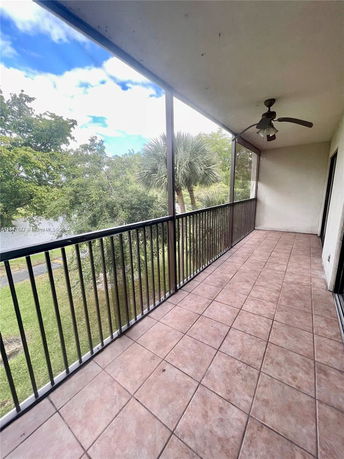 Balcony with tiled floor and railing overlooking a view with trees.