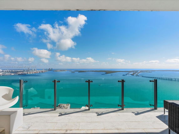 Panoramic view of the ocean and skyline from a high-rise building balcony.