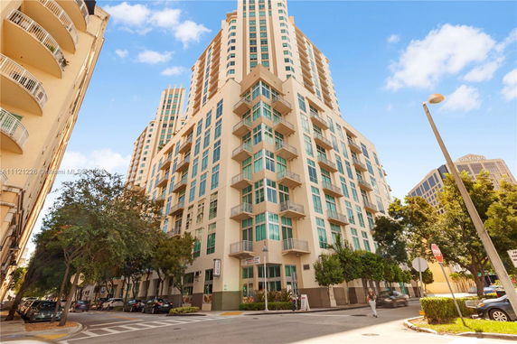 Front view of a tall modern apartment building with multiple balconies.