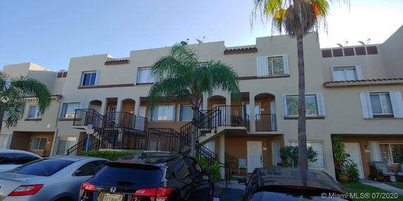 Front view of a multi-story residential building with external staircases and balconies.