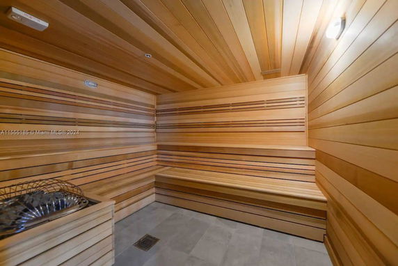 Interior view of a wooden sauna room with benches and heating element.