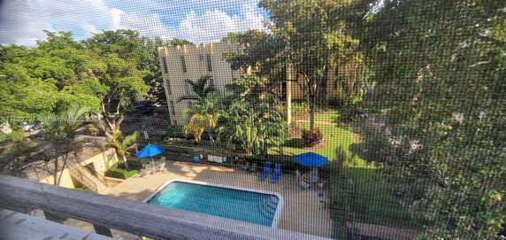 View of a swimming pool surrounded by greenery and trees.
