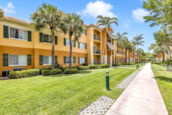 Front view of a multi-story building with palm trees and a walkway.
