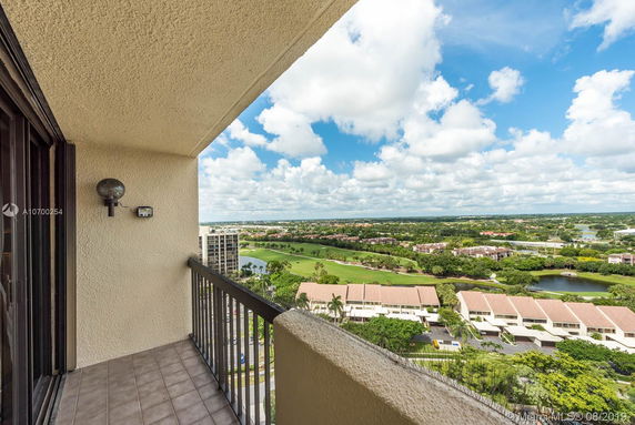 Balcony view from a high-rise building overlooking a vast landscape with residential areas and greenery.