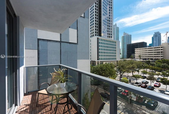 View from a balcony overlooking urban buildings and a cityscape.