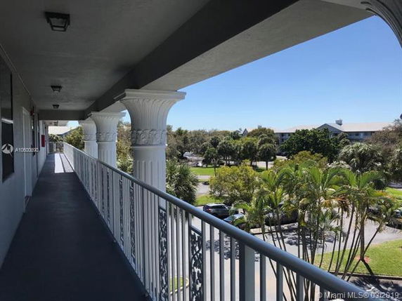 View from an elevated walkway with columns, overlooking trees and buildings.