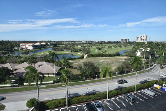 View of a golf course with palm trees and nearby residential buildings.