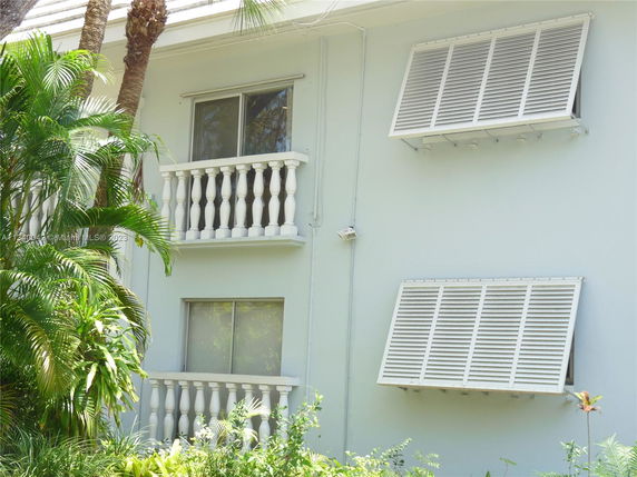 Side view of a building with small balconies and louvered windows.