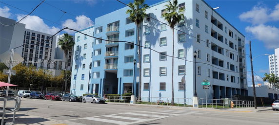 Front view of a multi-story blue apartment building with balconies.