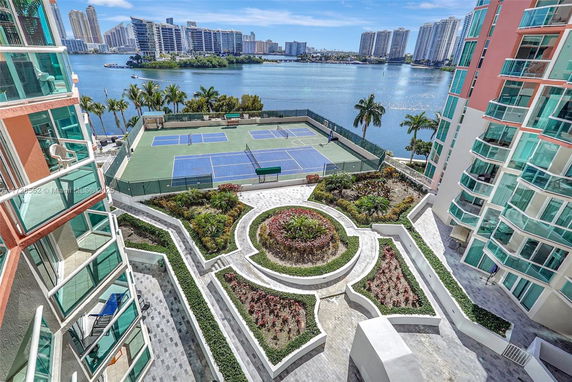 View of outdoor tennis courts and landscaped garden between residential buildings.