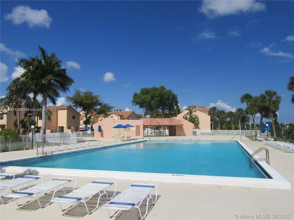 Outdoor swimming pool area with lounge chairs and nearby buildings.