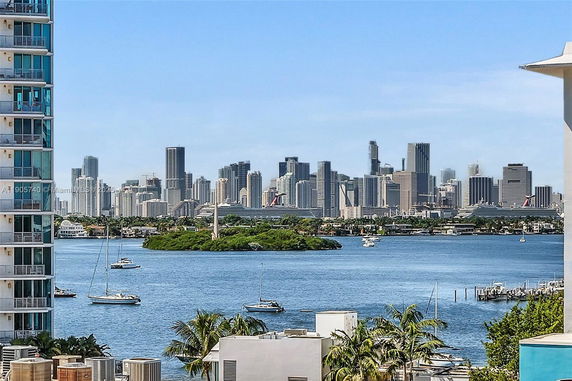 Panoramic view of a city skyline with water and boats in the foreground.