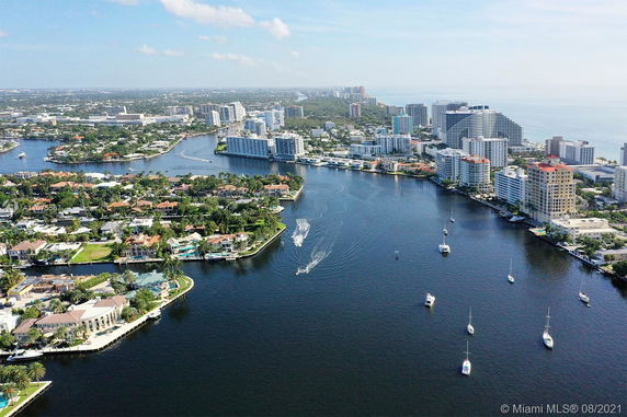 Aerial view of waterfront buildings and boats in a city landscape.