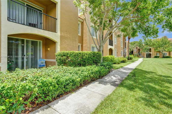 Front view of a multi-story apartment building with balconies and landscaped surroundings.