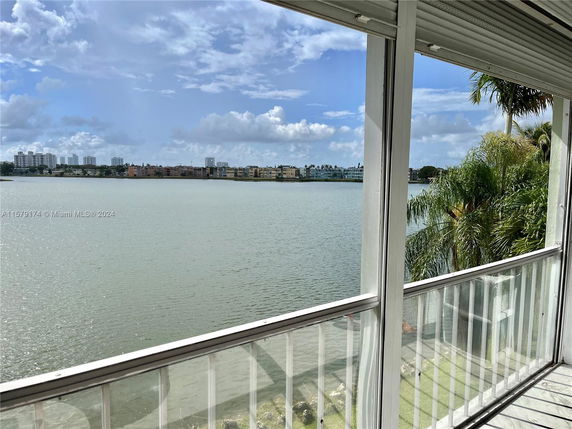 View from a balcony overlooking a body of water with city buildings in the distance.
