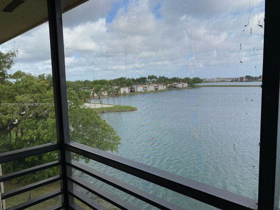 View of a lake and surrounding trees from a building's window.