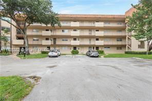 Front view of a multi-story apartment building with parking in front.