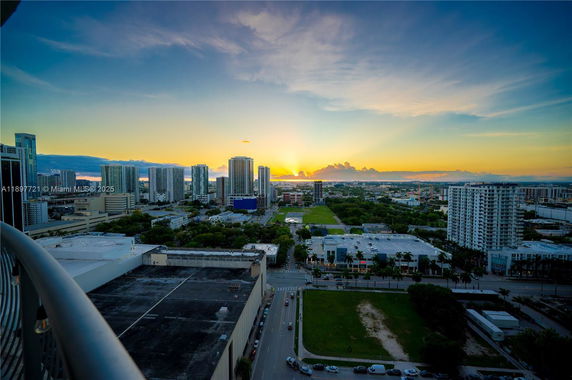 Panoramic view of a cityscape with tall buildings and a sunset in the background.