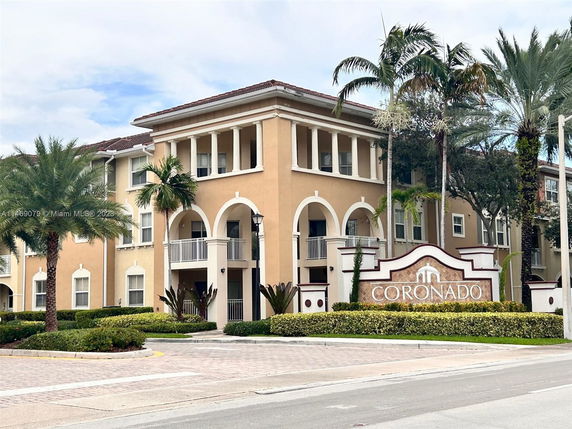 Front view of a multi-story residential building with arches and balconies.