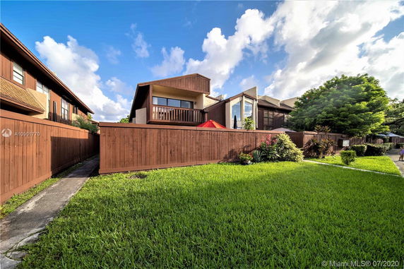 Front view of a multi-story house with a wooden fence and balcony.