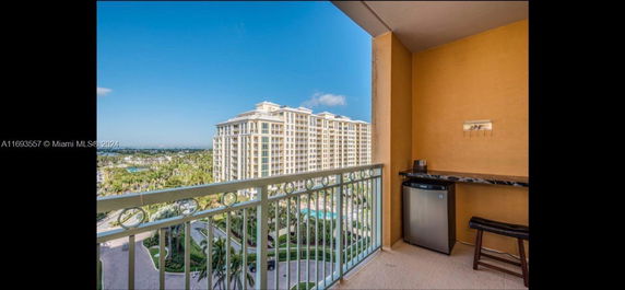 View from a balcony overlooking a tall residential building and surrounding landscape.