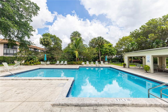 Outdoor swimming pool with surrounding lounge chairs and umbrellas.