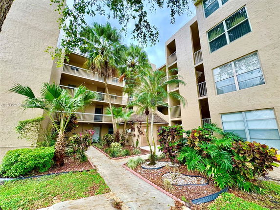 Front view of a multi-story residential building with balconies and surrounding landscaping.