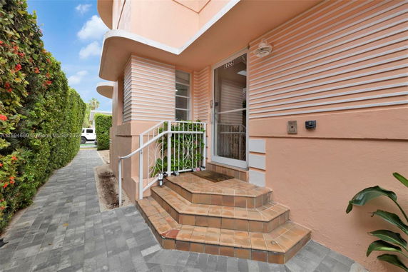 Side view of a pink building entrance with steps and railing.