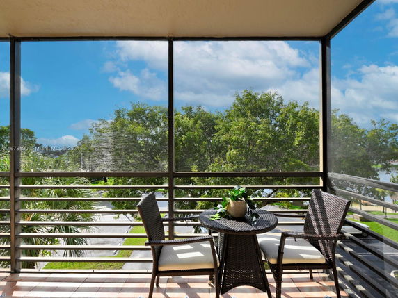 Balcony view showing surrounding greenery and sky.