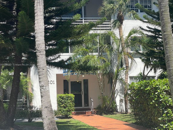 Front view of a multi-story building with a prominent entrance and surrounding greenery.