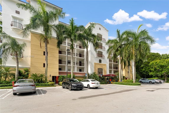 Front view of a multi-story residential building with balconies and an arched entrance.