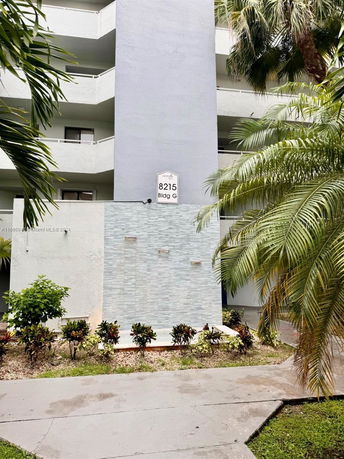 Front view of a multi-story building with balconies and a sign reading '8215 Bldg G'.