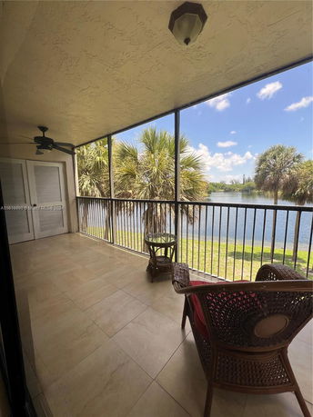 View from a balcony overlooking a lake and palm trees.