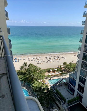 View of the ocean and beach seen from a high-rise building balcony.