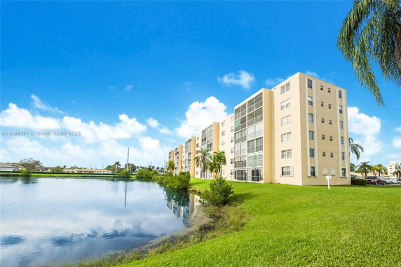 Front view of a multi-story apartment building next to a water body.