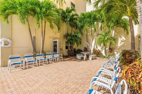 Outdoor area with lounge chairs and palm trees against a building.