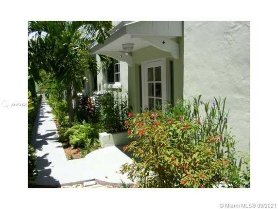 Side view of a house with a pathway and plants.