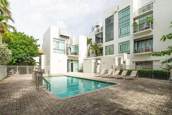 Outdoor swimming pool area adjacent to a modern multi-story building.