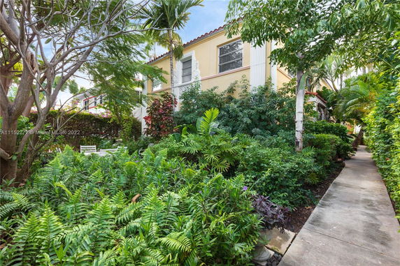 Front view of a two-story house surrounded by lush greenery and trees.