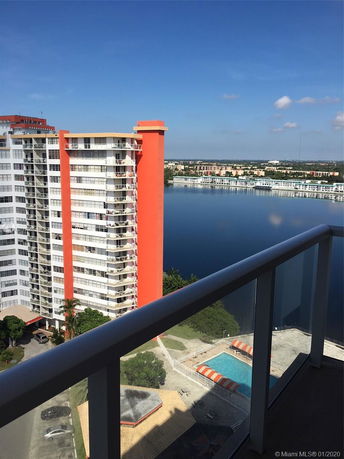View from a high-rise building balcony overlooking another high-rise and a large body of water.