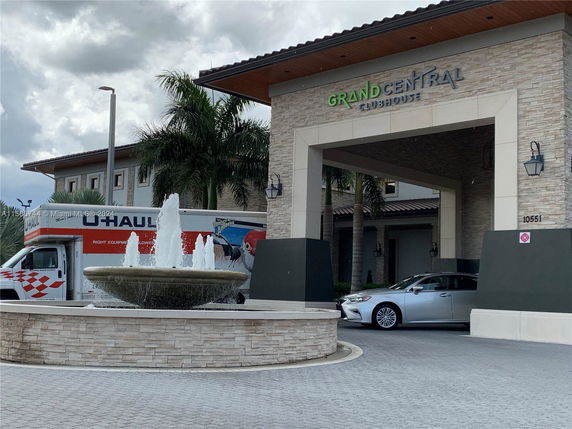 Front view of a clubhouse entrance with a circular driveway and water fountain.
