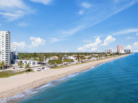 Wide-angle view of a coastal area with a beach and multiple buildings.