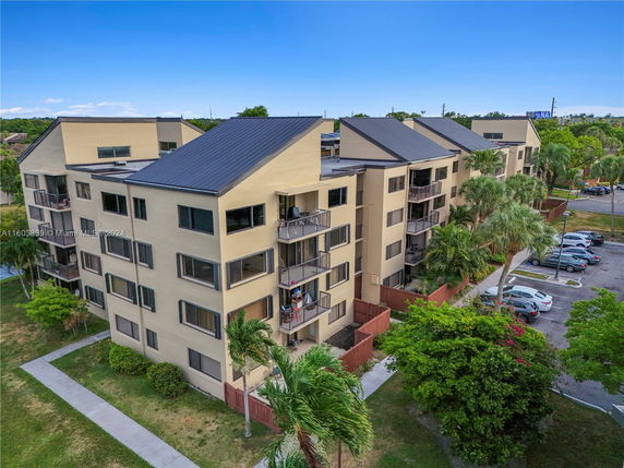 Front view of a multi-story apartment building with balconies and a sloped roof.
