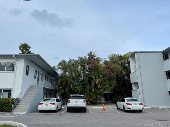 Outdoor parking area in front of a residential building with two stories.