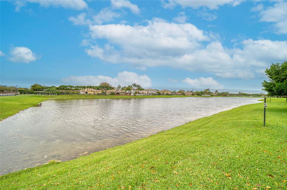 View of a lake with houses and trees in the background.