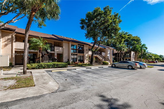 Front view of a multi-story residential building with balconies and parking spaces.