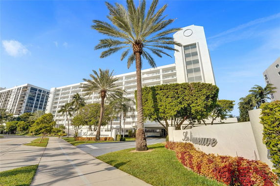 Front view of a multi-story residential building with palm trees in front.