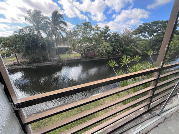 View from a balcony overlooking a canal with trees and vegetation.