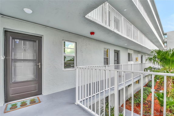 Exterior view of a residential building with multi-story walkways lined with white railings and windows.