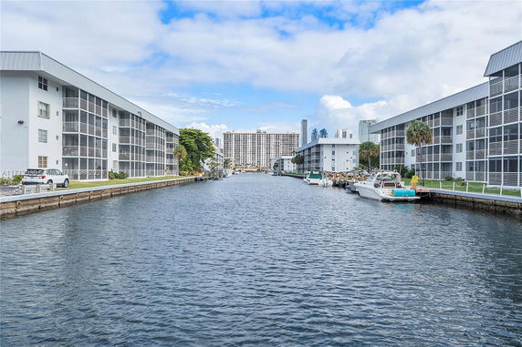 View of a waterway flanked by apartment buildings with boats docked along the sides.
